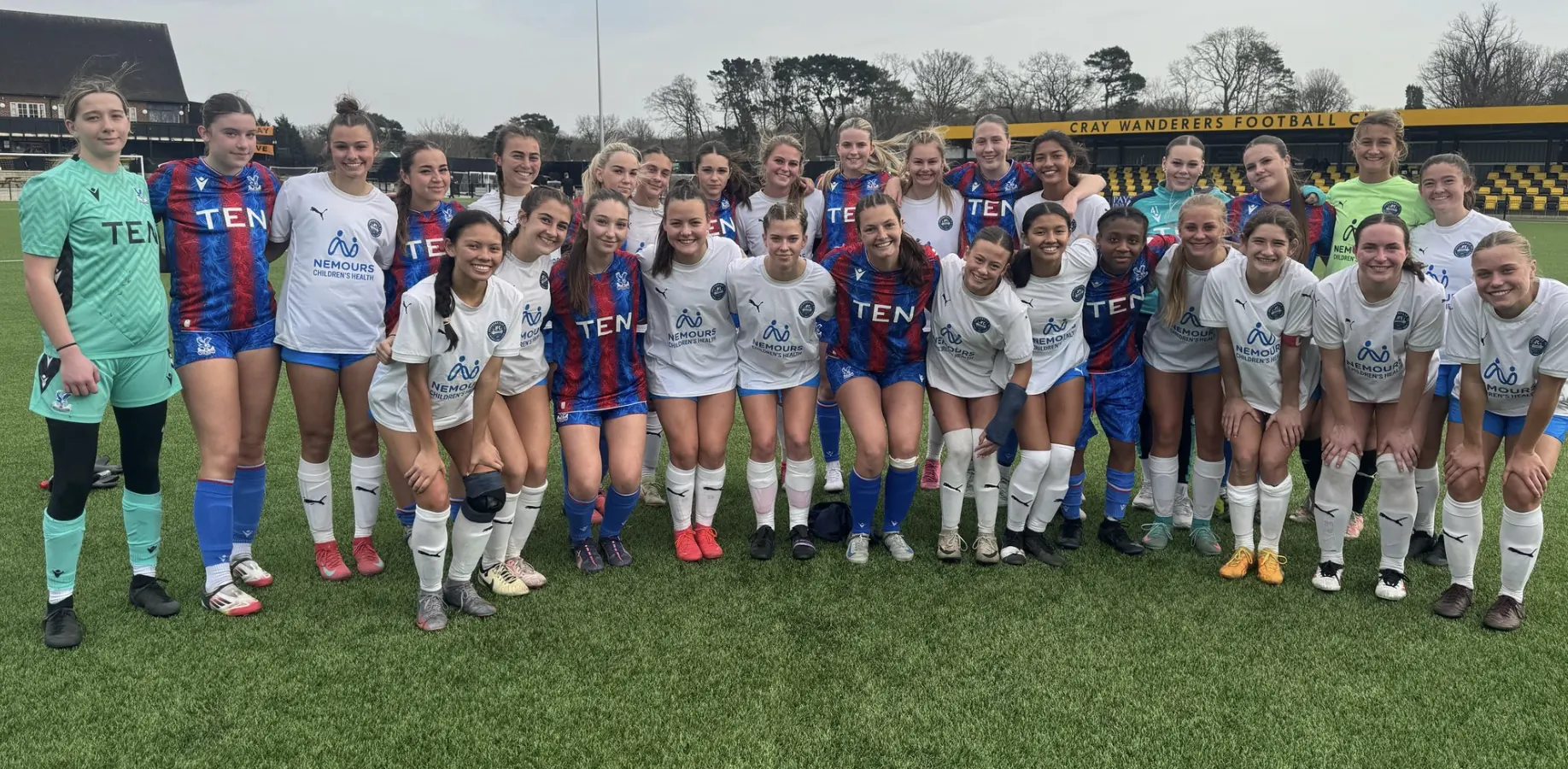 Jacksonville FC girls in white with Crystal Palace women’s academy players in red and blue, joint squad photo on a 3G pitch